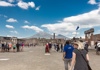 A group of people walking in Pompeii with columns and a the Vesuvius in the background