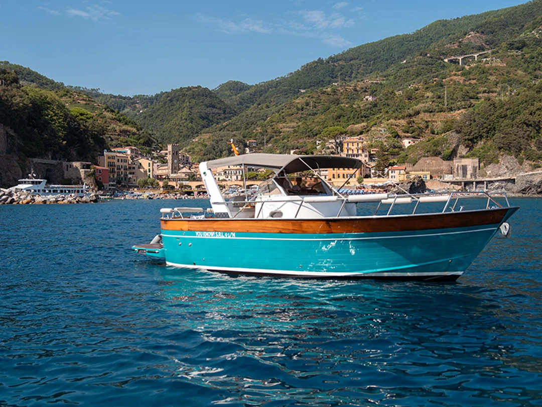 Turquoise Italian Riviera motorboat cruising off the coast of Monterosso al Mare in Cinque Terre.