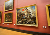 A couple looking at the Mona Lisa while visiting the Louvre Museum.