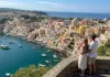 Couple overlooking the Marina Corricella harbor in Procida from a scenic viewpoint.