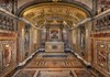 An opulent church interior with gilded ceilings, intricate frescoes, and polished marble floors reflecting the warm glow of chandeliers.