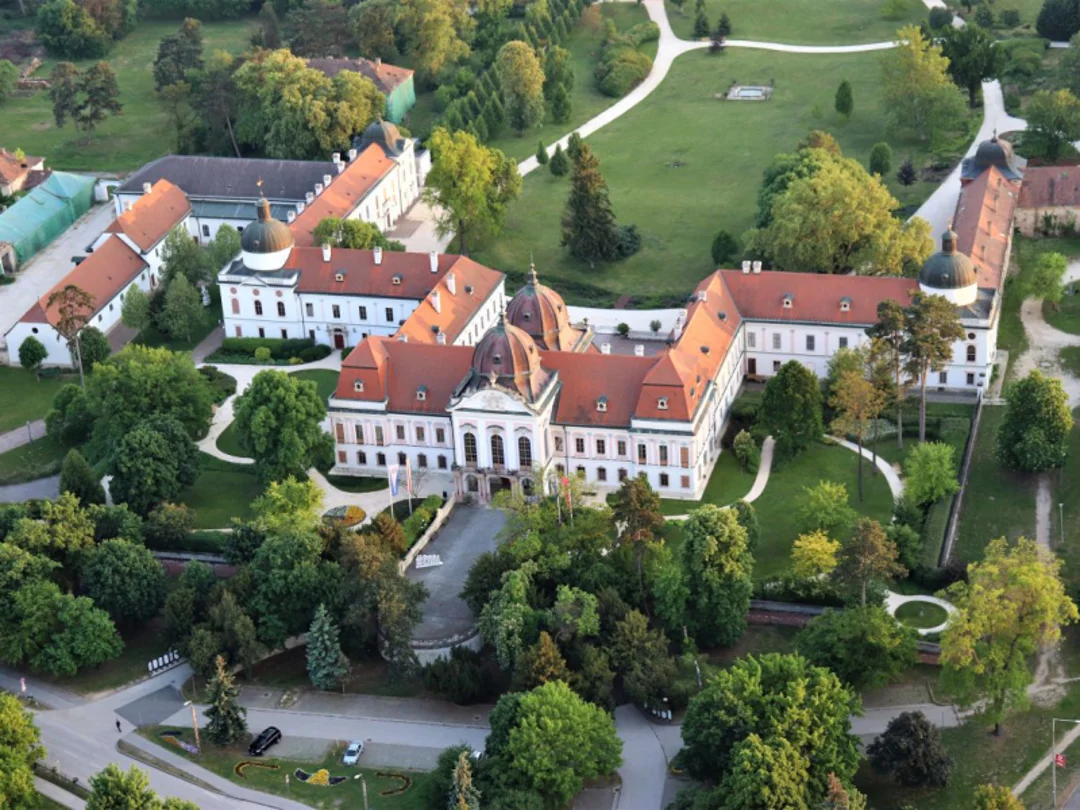 High-angle view of Gödöllő Palace surrounded by landscaped parkland.