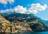 A group of tourists taking selfies in front of the colorful cliffs of Positano. 