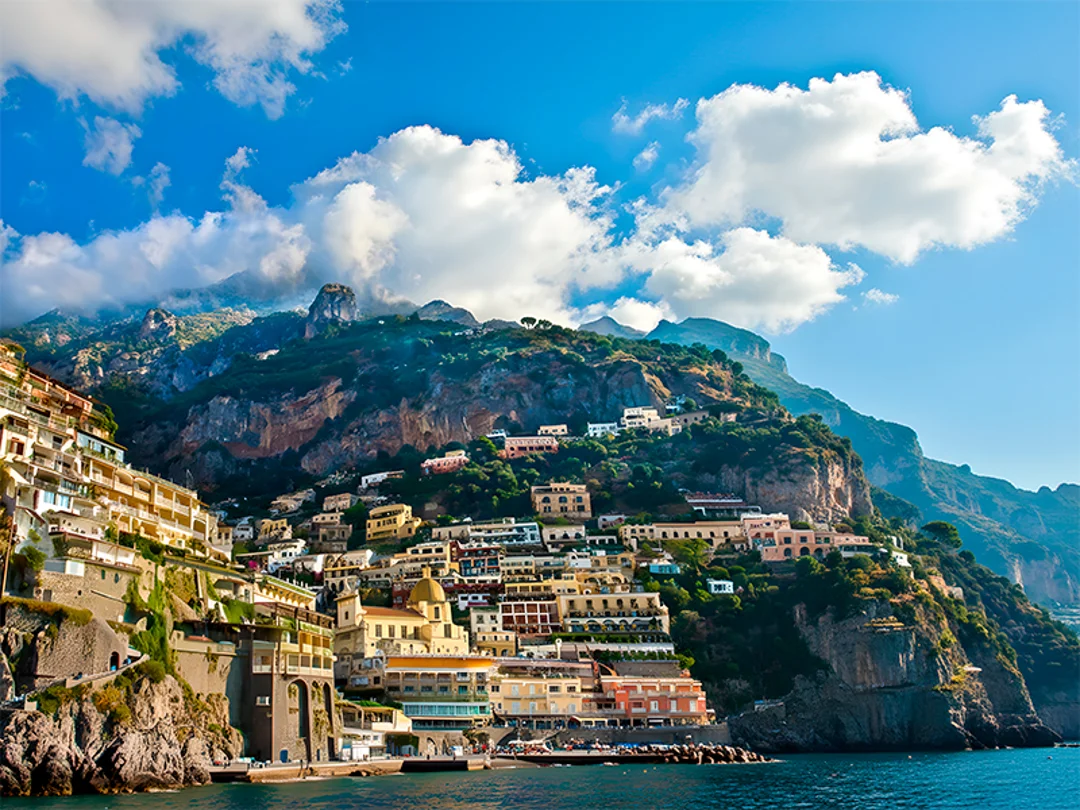 A group of tourists taking selfies in front of the colorful cliffs of Positano. 