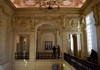 An ornate museum hall with gilded ceilings and grand chandeliers, showcasing its elegant historic architecture.