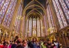 Tourists standing inside of Sainte-Chapelle with stained glass windows in Paris. 