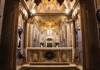 An ornate altar inside a historic church, decorated with golden frescoes, intricate carvings, and sacred relics.