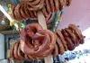 Fresh pretzels hanging on a wooden display stand at a market stall.