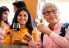Two people smiling and holding glasses of red and white wine inside a tasting room.