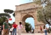 Two tourists standing under the Arch of Titus with their guide from The Tour Guy.