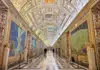 A visitor stands in a doorway, silhouetted against the bright golden light of the Vatican’s historic corridors.