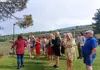 Group of visitors standing on a vineyard lawn listening to a guide during a wine tour.