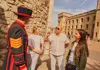 A group of tourists taking a picture with a Tower of London Beefeater