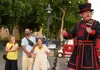 A group of tourists listening a Tower of London Beefeater