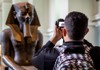 Photo of a tourist taking a picture of Egyptian Mummies inside of the British Museum in London. 