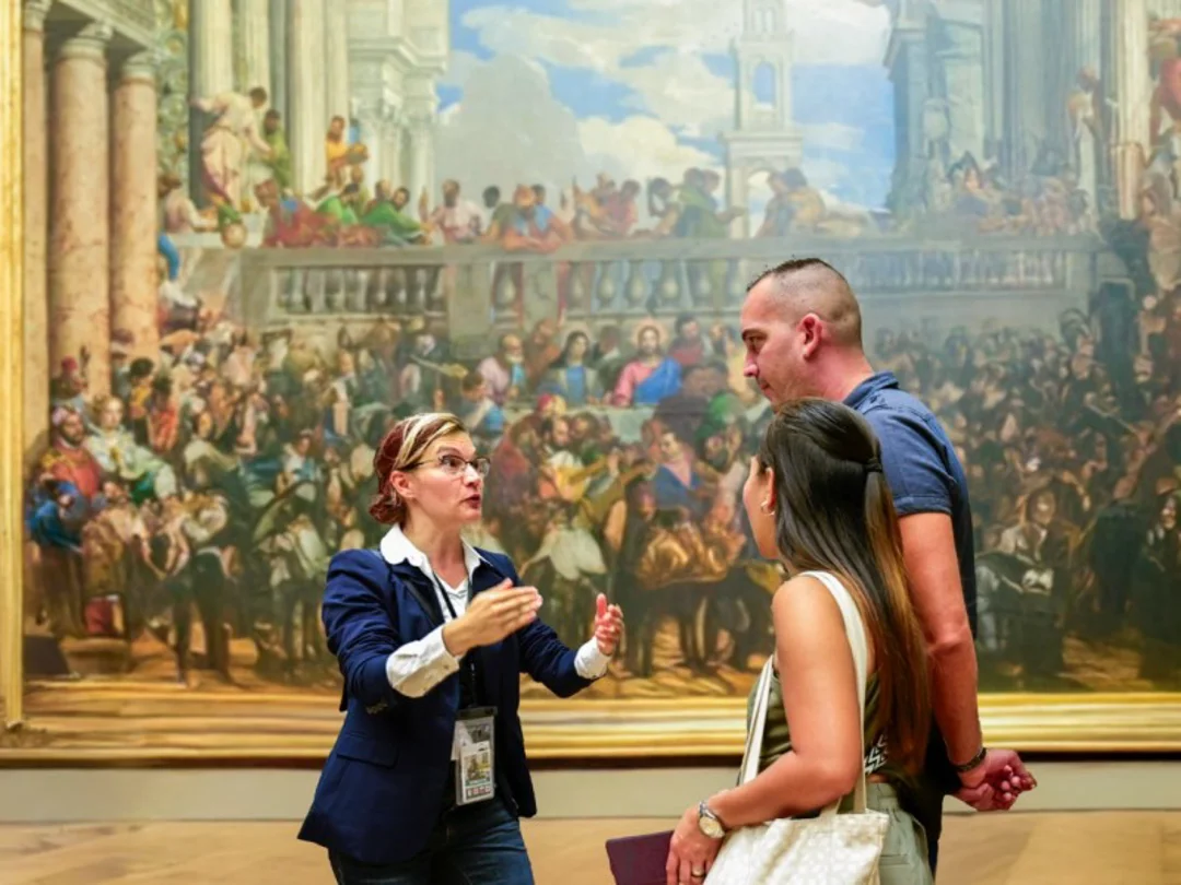 A woman in the Louvre taking a photo of the Mona Lisa while listening to their guide from The Tour Guy.