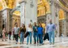 Small group walking through the interior of St. Peter’s Basilica beneath gilded ceilings and towering columns