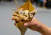 Hand holding a paper cone filled with freshly fried seafood during a Naples street food tasting.