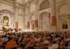 A group of people sitting in chairs in the Church of San Vidal