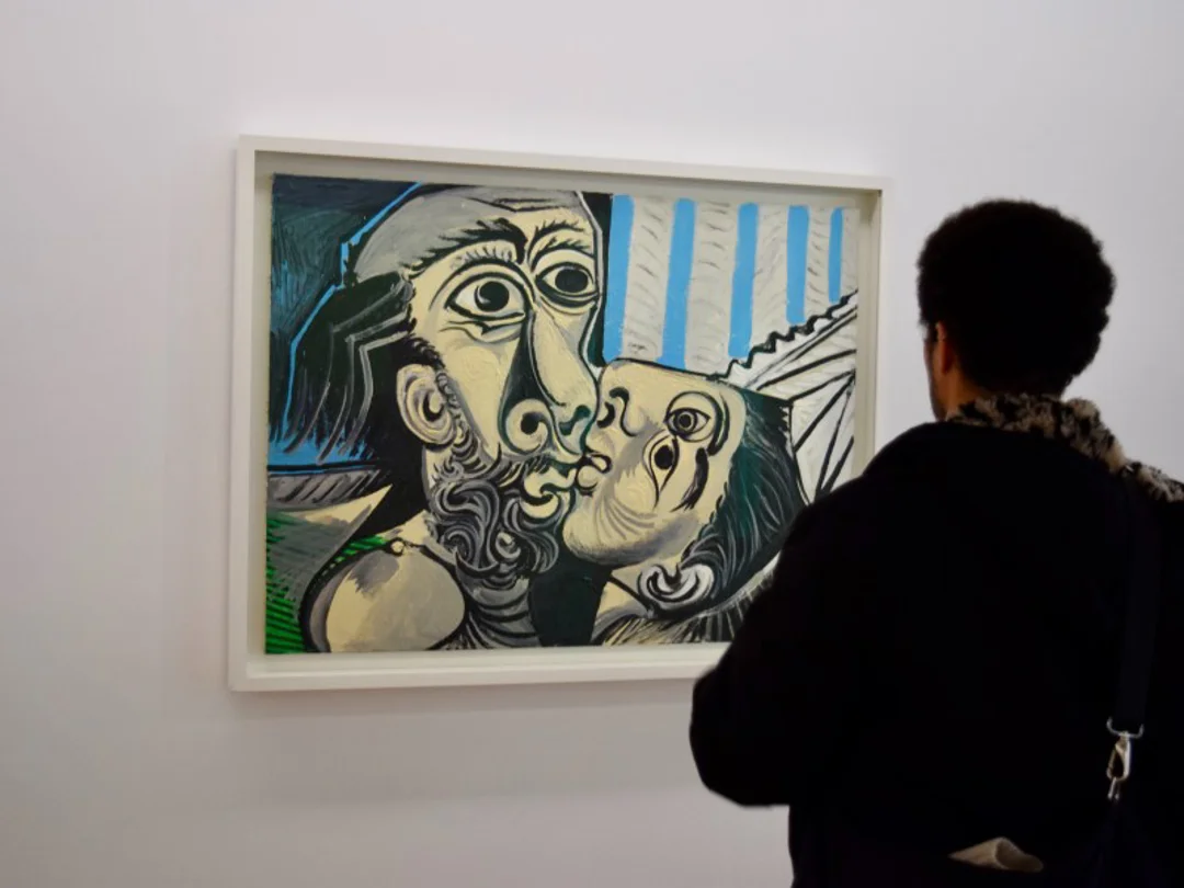 A visitor observes a striking Picasso painting in a museum, silhouetted against the artwork.