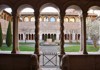 A peaceful cloister with arched walkways and a lush courtyard, offering a serene retreat within a historic monastery.