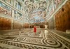 Visitors stand inside the Sistine Chapel, gazing up at Michelangelo’s masterpiece on the ceiling.