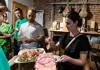 Chef serving freshly made gnocchi to guests seated at a table during a cooking class