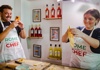 A man taking pictures of a woman making food and smiling