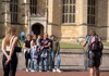 A tour guide speaks to a small group outside a historic building, gesturing as visitors listen attentively.
