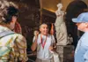 Tour guide explaining a marble sculpture to visitors inside the Louvre Museum