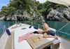 Guest relaxing on the bow of a boat near rocky coves and green coastal cliffs