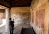 A woman taking a picture of an ancient design on a wall in Pompeii