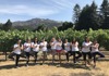 Group doing yoga pose in front of vineyard