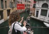 A tour guide waving to tourists inside of a gondola in Venice.