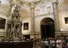 Stained-glass window inside Seville Cathedral depicting colorful religious imagery.
