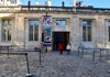 The entrance of a historic art museum, with a grand façade and a visitor standing in the cobblestone courtyard.