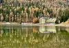 Lakeside hotel reflected in calm water, surrounded by autumn forest and mountains