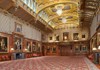 A grand gallery in a historic palace showcases gilded ceilings, elaborate paintings, and richly decorated walls.