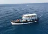 Aerial view of a two-deck excursion boat carrying passengers on open water.