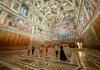 A small group explores an ornately decorated corridor in the Vatican Museums, surrounded by golden-hued ceilings and Renaissance artwork.