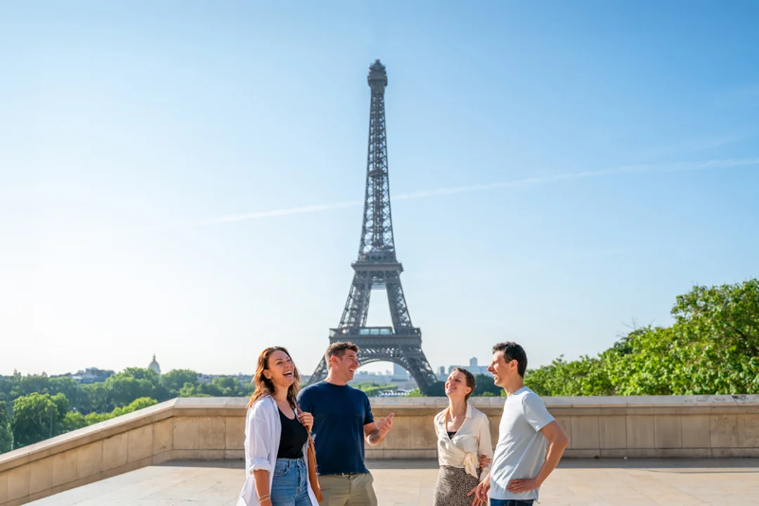 A group of tourists on the 2nd level of the Eiffel Tower drinking champagne with their guide from The Tour Guy.
