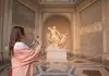 A long, empty hallway in the Vatican Museums showcases intricate frescoes and elaborate gold-trimmed ceilings.