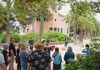 A group of tourists listening to a tour guide outside of Gaudi's House inside of Park Guell in Barcelona. 