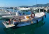 Traditional Ligurian boat docked in a busy marina with calm turquoise water.