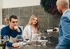 Man pondering as instructor hands glass to woman