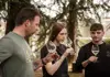 Three guests smelling white wine during a guided tasting outdoors among trees