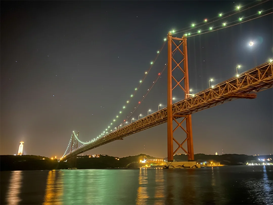 25 de Abril Bridge illuminated with city lights at night