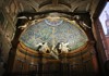 A stunning blue and gold mosaic depicting religious figures covers the curved apse of a grand basilica.