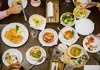 Overhead view of multiple Austrian dishes, including schnitzel, salads, potatoes, and vegetables on a wooden table.