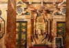 Religious sculpture inside the Seville Cathedral, displayed against an ornate marble altarpiece.